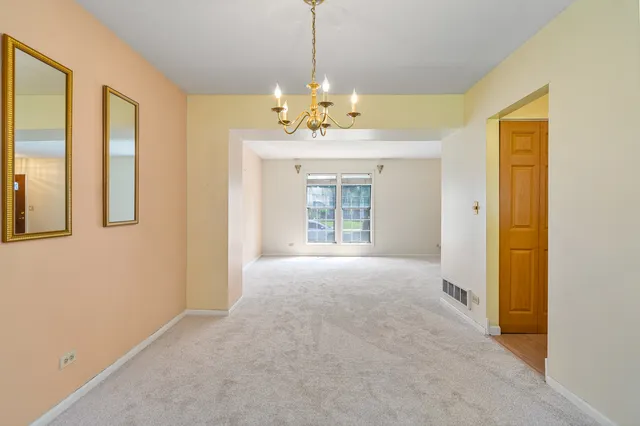 a view of an empty room with chandelier and a window