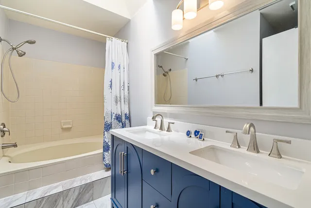 a bathroom with a sink double vanity granite tub shower and a mirror