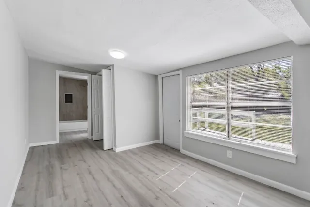 a view of an empty room with a window and wooden floor