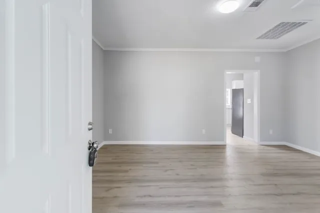 a view of an empty room with wooden floor and a window