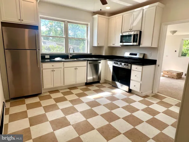 a kitchen with a checkered floor and steel appliances