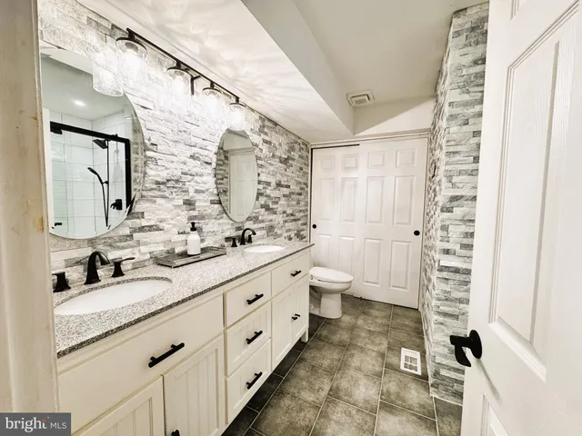 a bathroom with a granite countertop sink a mirror and shower
