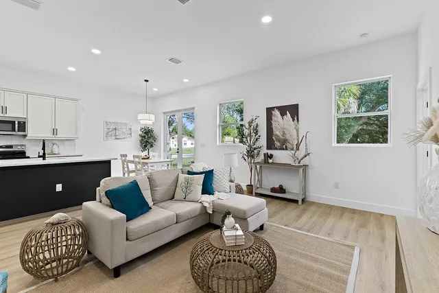 a living room with furniture a rug and kitchen view