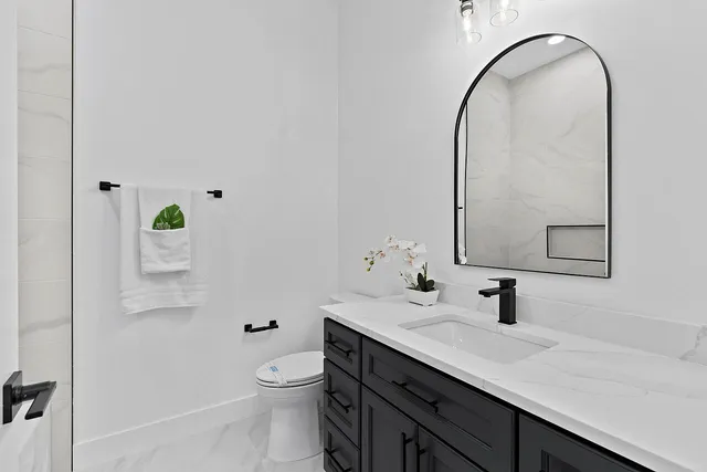 a bathroom with a granite countertop toilet sink and mirror