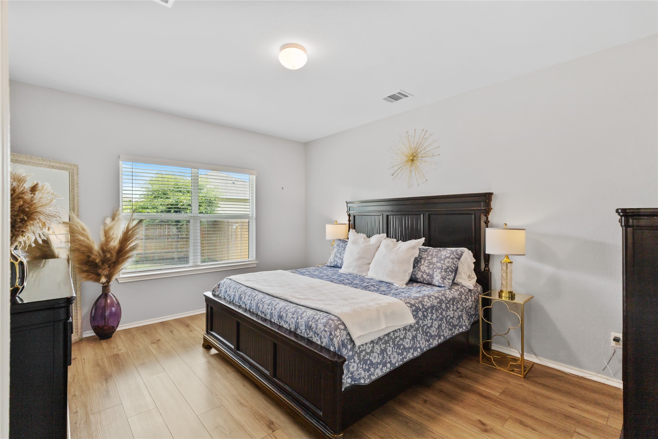 425 Perfect World Loop Jarrell, TX 76537 - Photo 11 of 29 Spacious bedroom featuring wood-finish flooring, a large window with blinds, and a ceiling-mounted light fixture