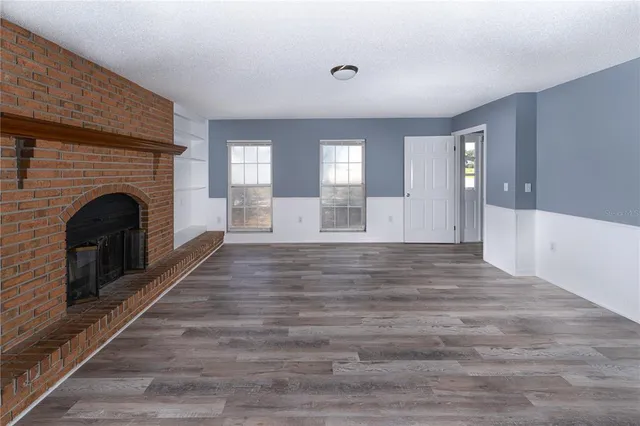 a view of empty room with fireplace and wooden floor
