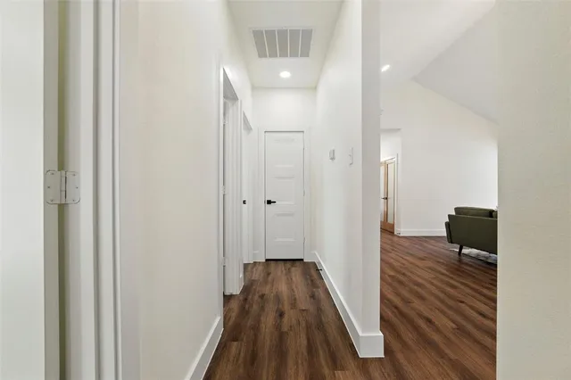 a view of a hallway with wooden floor and a bathroom