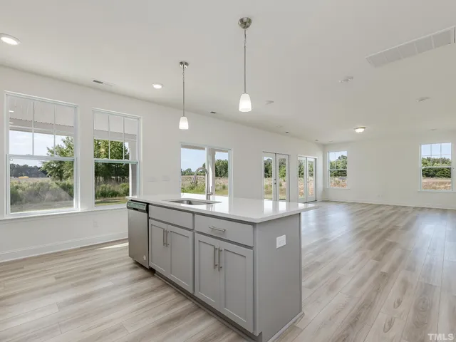 a large kitchen with kitchen island a large window a sink and stainless steel appliances