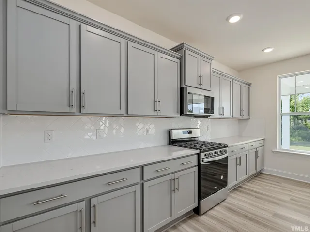 a kitchen with stainless steel appliances granite countertop a sink a stove and a microwave