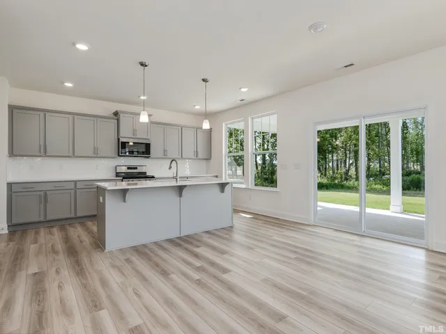 a view of kitchen with kitchen island wooden floor center island and stainless steel appliances