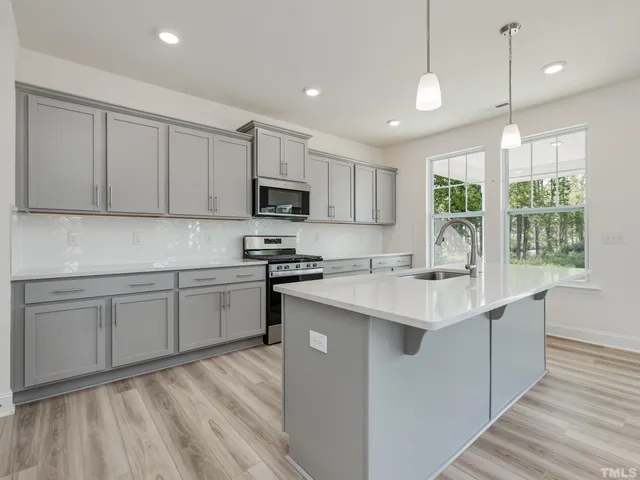 a kitchen with kitchen island granite countertop a sink appliances cabinets and a counter top space