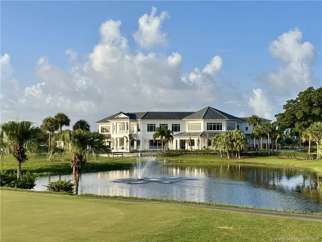 a front view of a house with a yard lake and outdoor seating