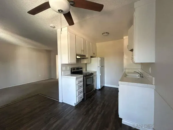 a kitchen with a sink cabinets stainless steel appliances and wooden floor
