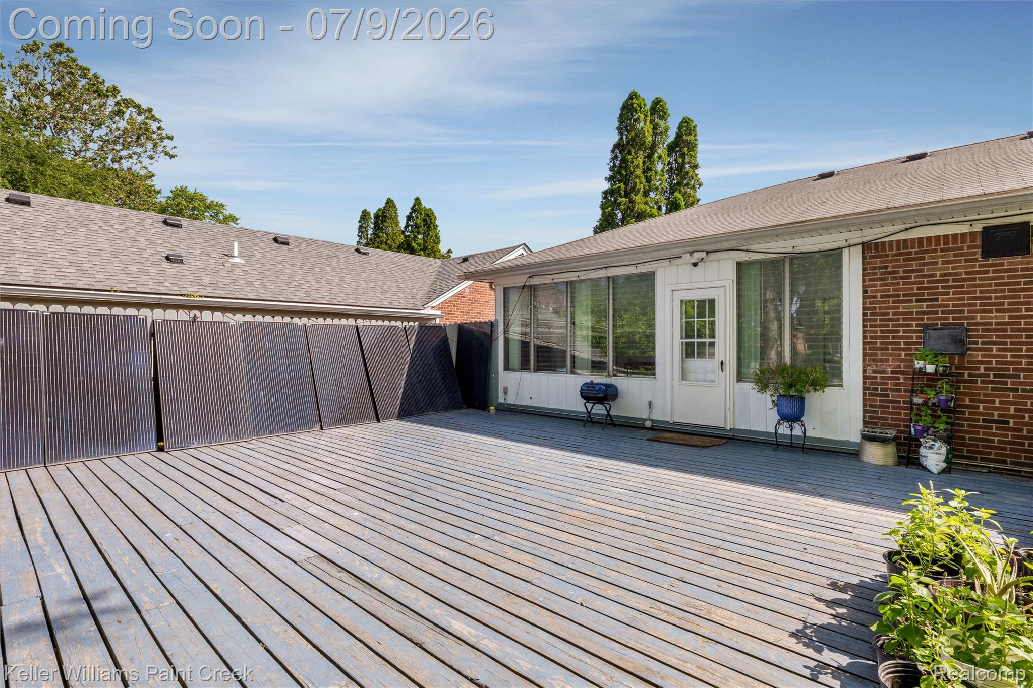 2731 Crooks Road Royal Oak, MI 48073 - Photo 32 of 34 Expansive outdoor deck featuring wood planking, an enclosed patio with multiple windows, and a brick exterior wall
