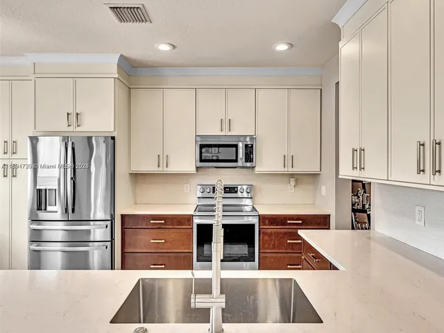 a kitchen with stainless steel appliances granite countertop a refrigerator and a stove top oven