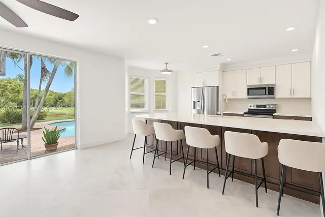 a kitchen with kitchen island a dining table chairs and a refrigerator