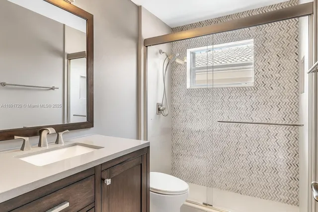 a bathroom with a granite countertop sink toilet and shower