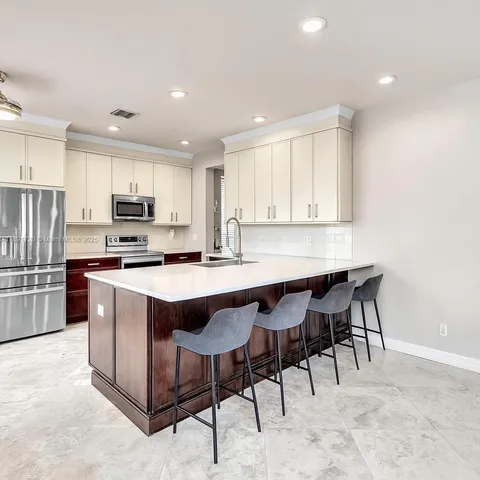 a kitchen with stainless steel appliances granite countertop a table chairs sink refrigerator and microwave