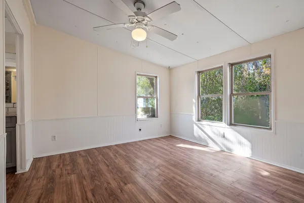 an empty room with wooden floor and windows