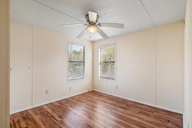 a view of an empty room with window and wooden floor