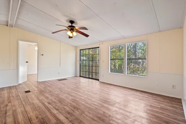 a view of an empty room with a window and wooden floor