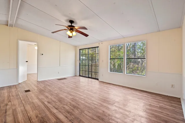 a view of an empty room with a window and wooden floor