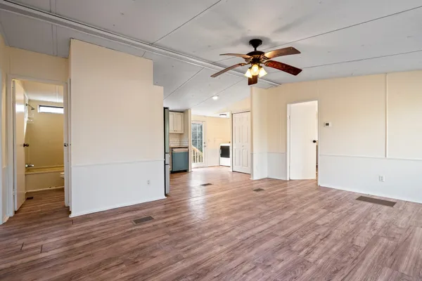 a view of a livingroom with a ceiling fan wooden floor and window