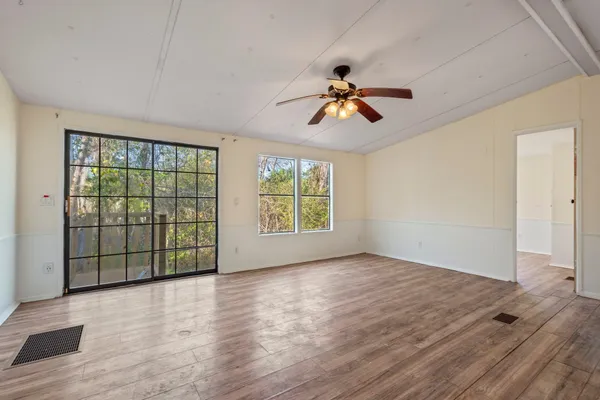 a view of empty room with wooden floor and fan