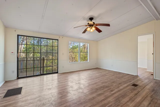 a view of empty room with wooden floor and fan