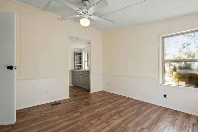 a view of empty room with wooden floor and fan