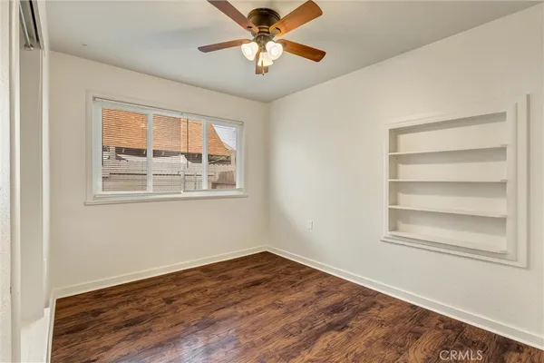 a view of an empty room with a window and wooden floor