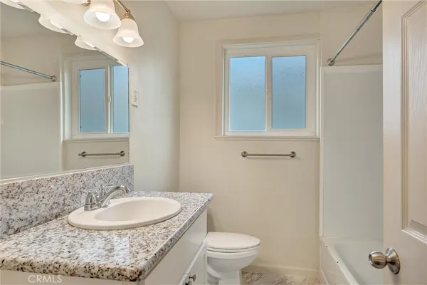 a bathroom with a granite countertop sink a toilet and a mirror