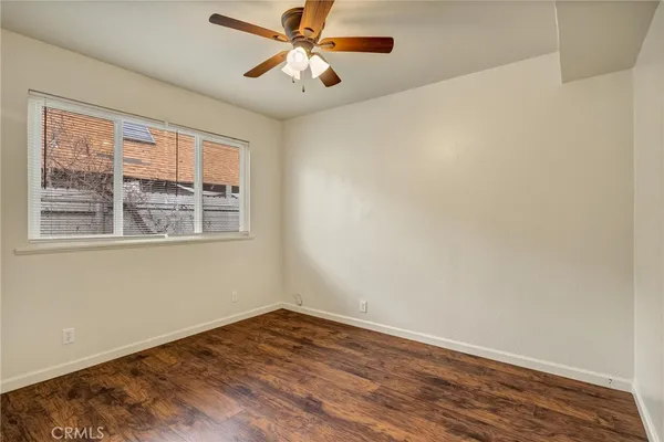 a view of empty room with wooden floor and fan