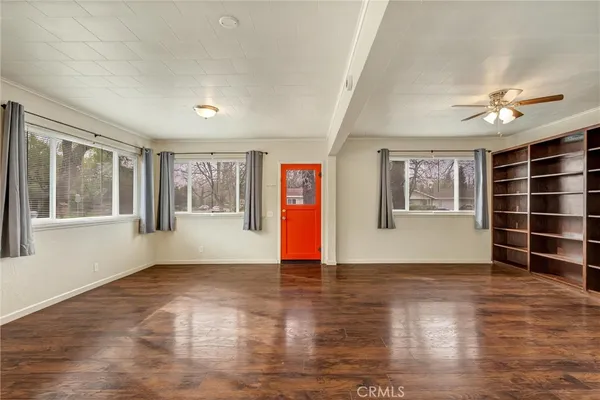 a view of an empty room with a window and wooden floor