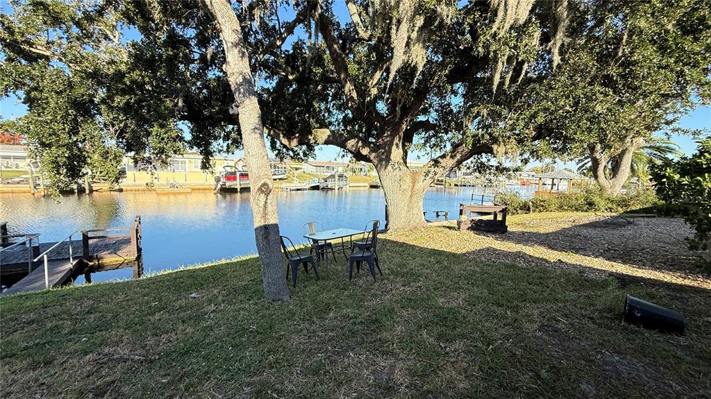 12611 1st Isle Hudson, FL 34667 - Photo 18 of 19 a view of a backyard with table and chairs and couches with wooden fence