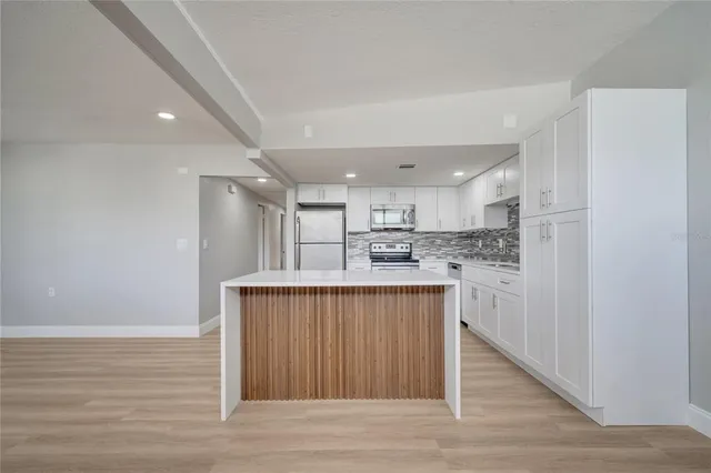a view of a kitchen with a refrigerator a ceiling fan and a wooden floor