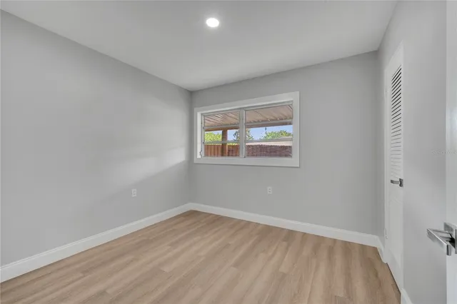 a view of an empty room with wooden floor and a window