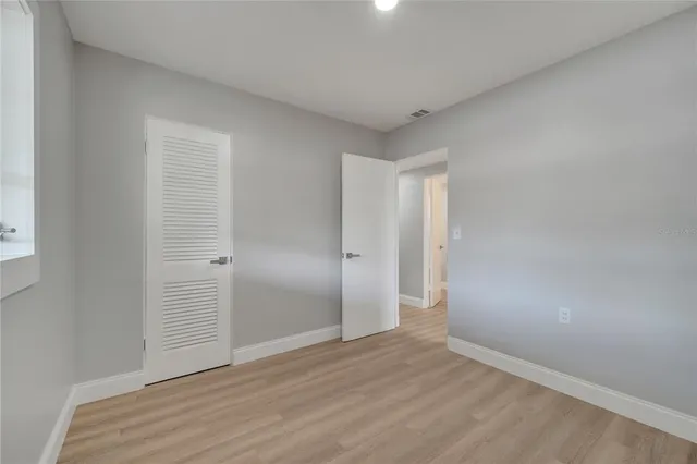 a view of an empty room with wooden floor and window