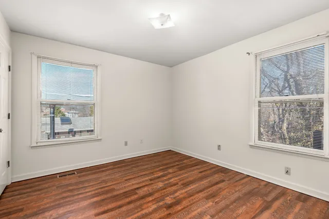 a view of empty room with window and wooden floor