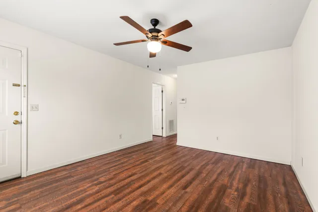 an empty room with wooden floor and ceiling fan