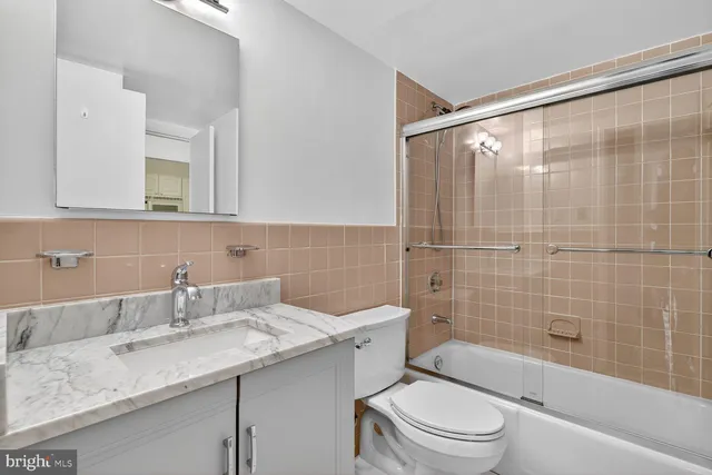 a bathroom with a granite countertop sink a toilet and shower