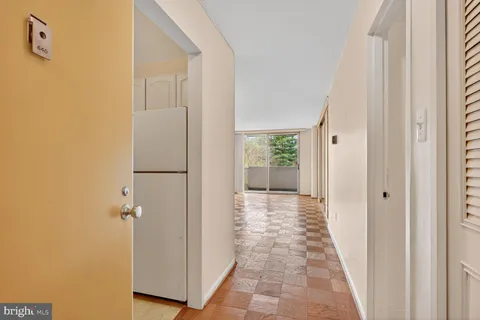 a view of a hallway with wooden floor and a bathroom