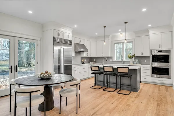 a kitchen with stainless steel appliances kitchen island granite countertop a dining table and chairs in it