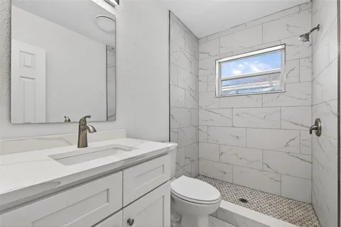 a bathroom with a granite countertop toilet sink and mirror