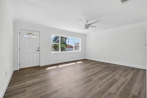 an empty room with wooden floor ceiling fan and windows