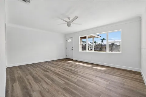 a view of an empty room with a window and wooden floor
