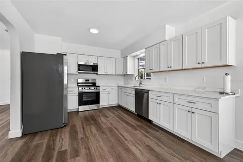 a kitchen with granite countertop white cabinets and stainless steel appliances