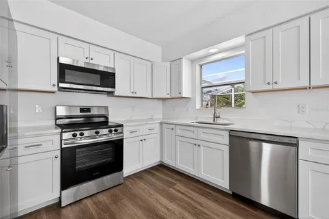 a kitchen with cabinets stainless steel appliances a sink and a window
