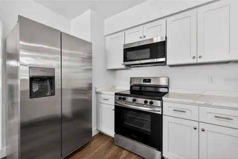 a kitchen with stainless steel appliances white cabinets a stove a microwave and a refrigerator