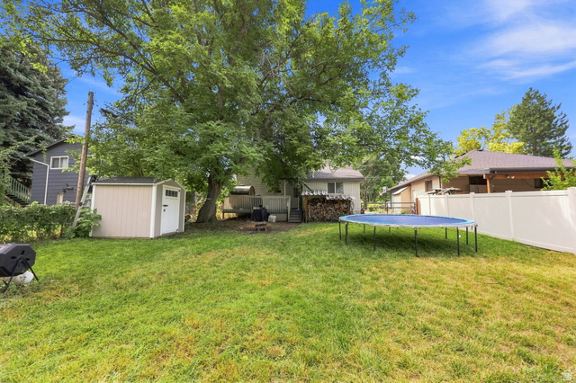 154 West 400 North Springville, UT 84663 - Photo 33 of 43 Expansive backyard featuring a manicured lawn, mature trees, a white vinyl fence, and a neutral-toned storage shed